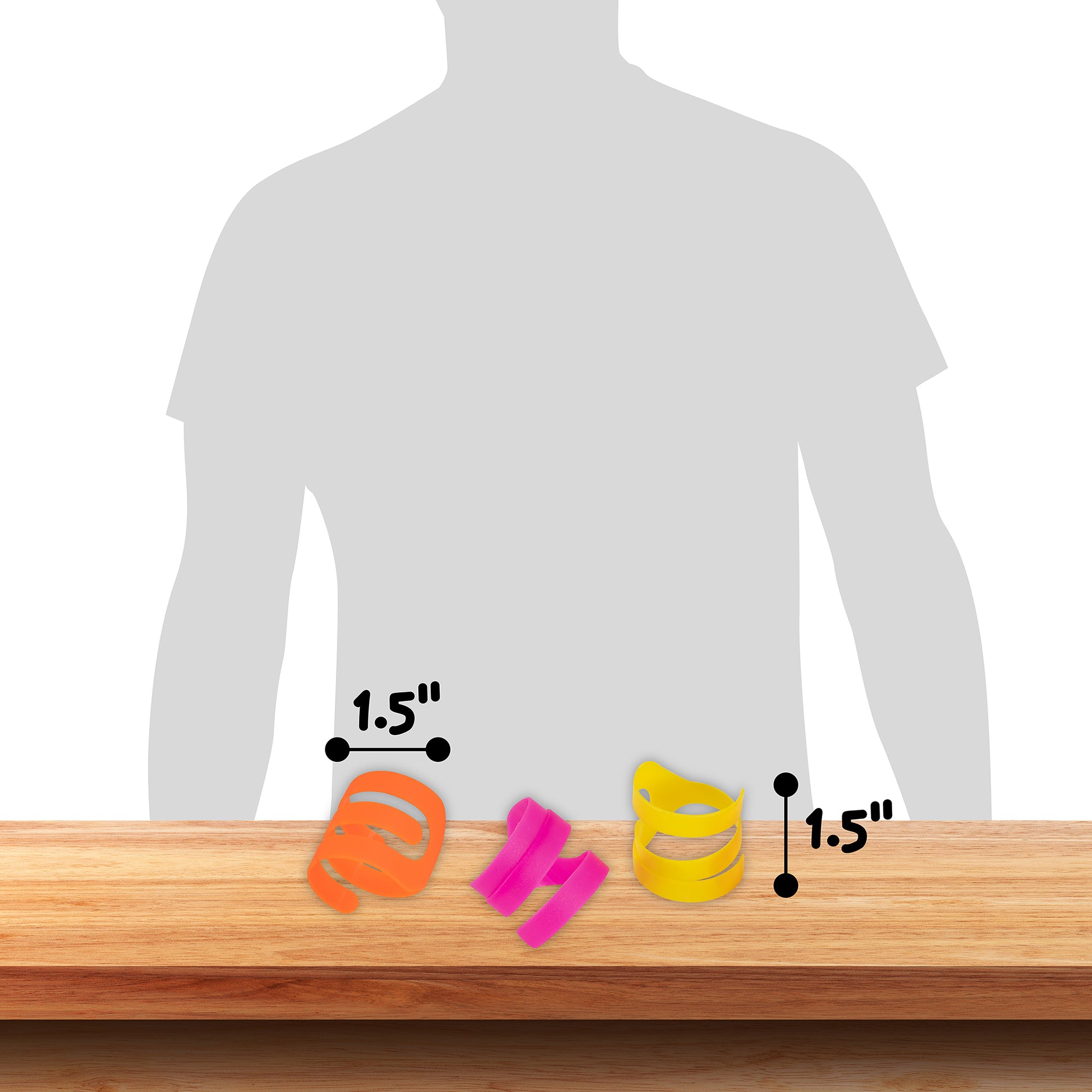 On a wooden surface lay three Pet-mates Looney Loops Cat Toys in bright neon orange, pink, and yellow, each 1.5 inches in diameter. A persons silhouette is faintly visible behind them.