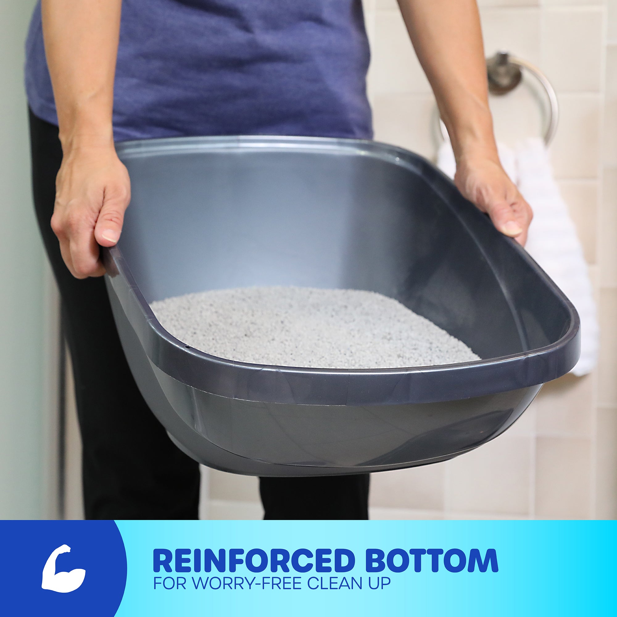 Person holding a gray Pet-mates Basic Hooded Cat Litter Pan, filled with litter. Text reads, Reinforced Bottom for Worry-Free Clean Up, next to a flexed arm icon. Background features a towel on a hook and an odor-absorbing filter for easy cleaning. Brand: Pet-mates.