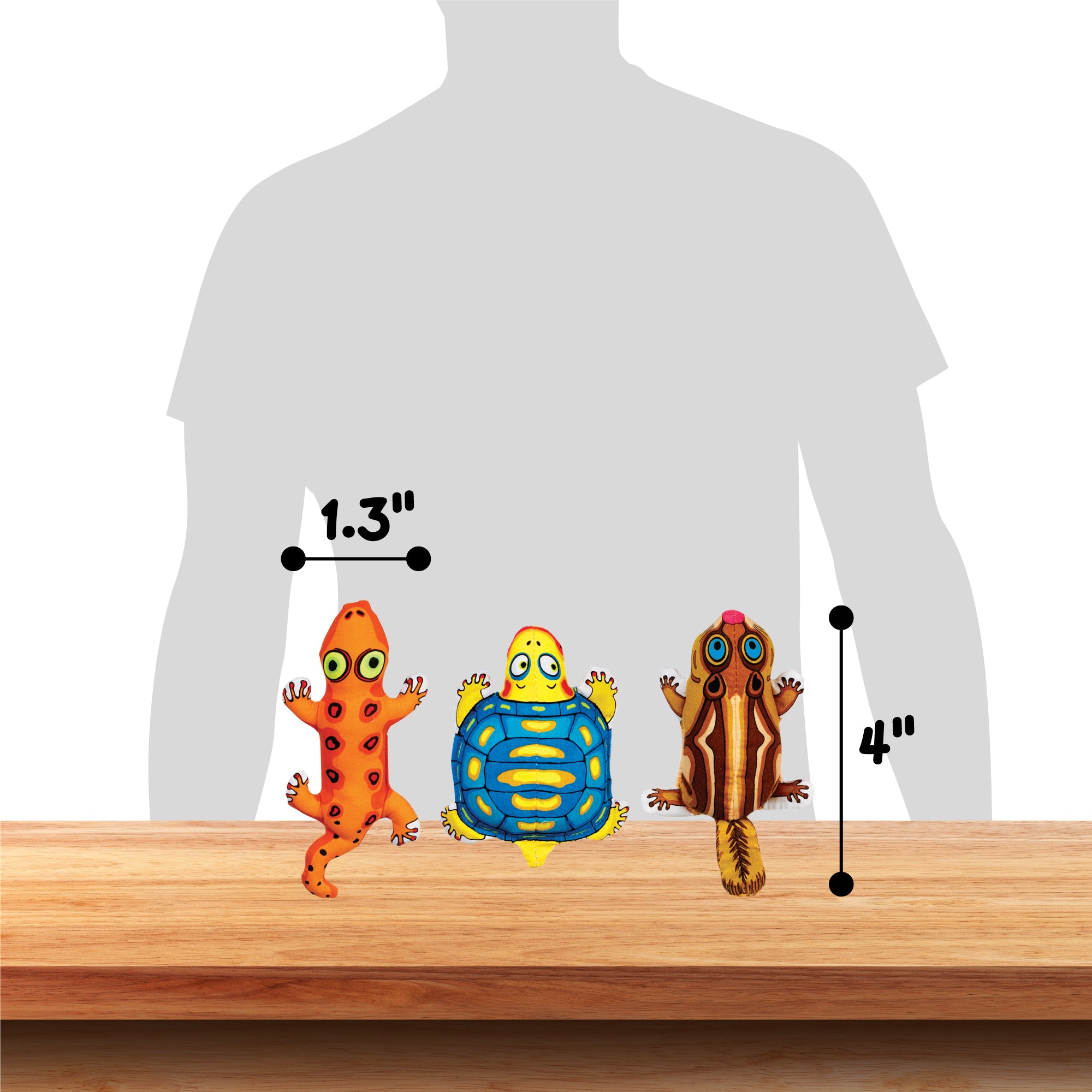 On the table are three colorful cartoon animals: a petite 1.3-inch red lizard, a blue turtle, and a 4-inch tall striped brown squirrel. They sit alongside durable FAT CAT Classic Crackler Cat Toys by Fatcat as a shadowy human figure looms in the background for size comparison.