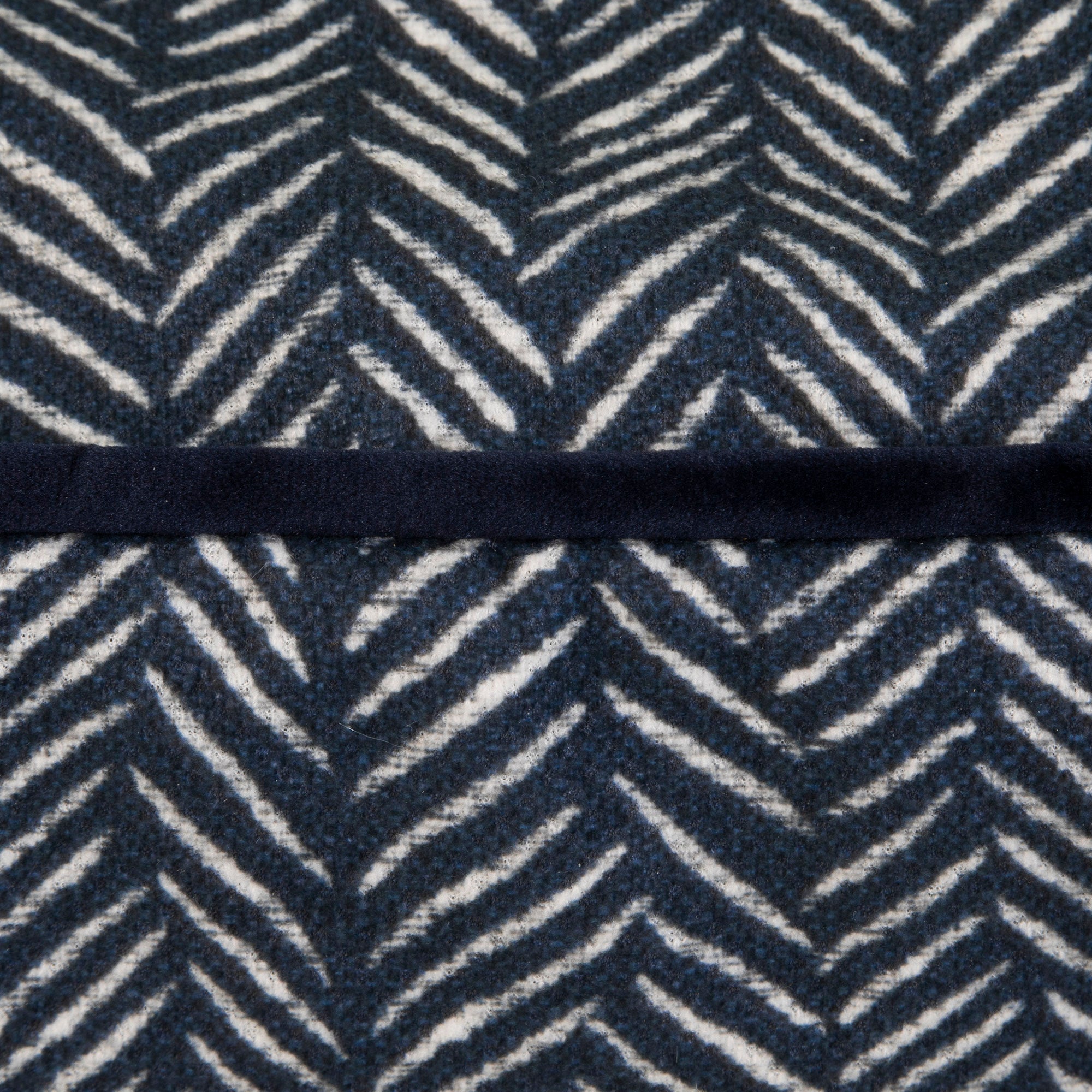Close-up of a textured fabric with a dark blue and white herringbone pattern resembling the cozy feel of the La-Z-Boy Gatson Indoor Outdoor Dog Bed. A narrow black strip runs horizontally across the center, dividing the pattern.