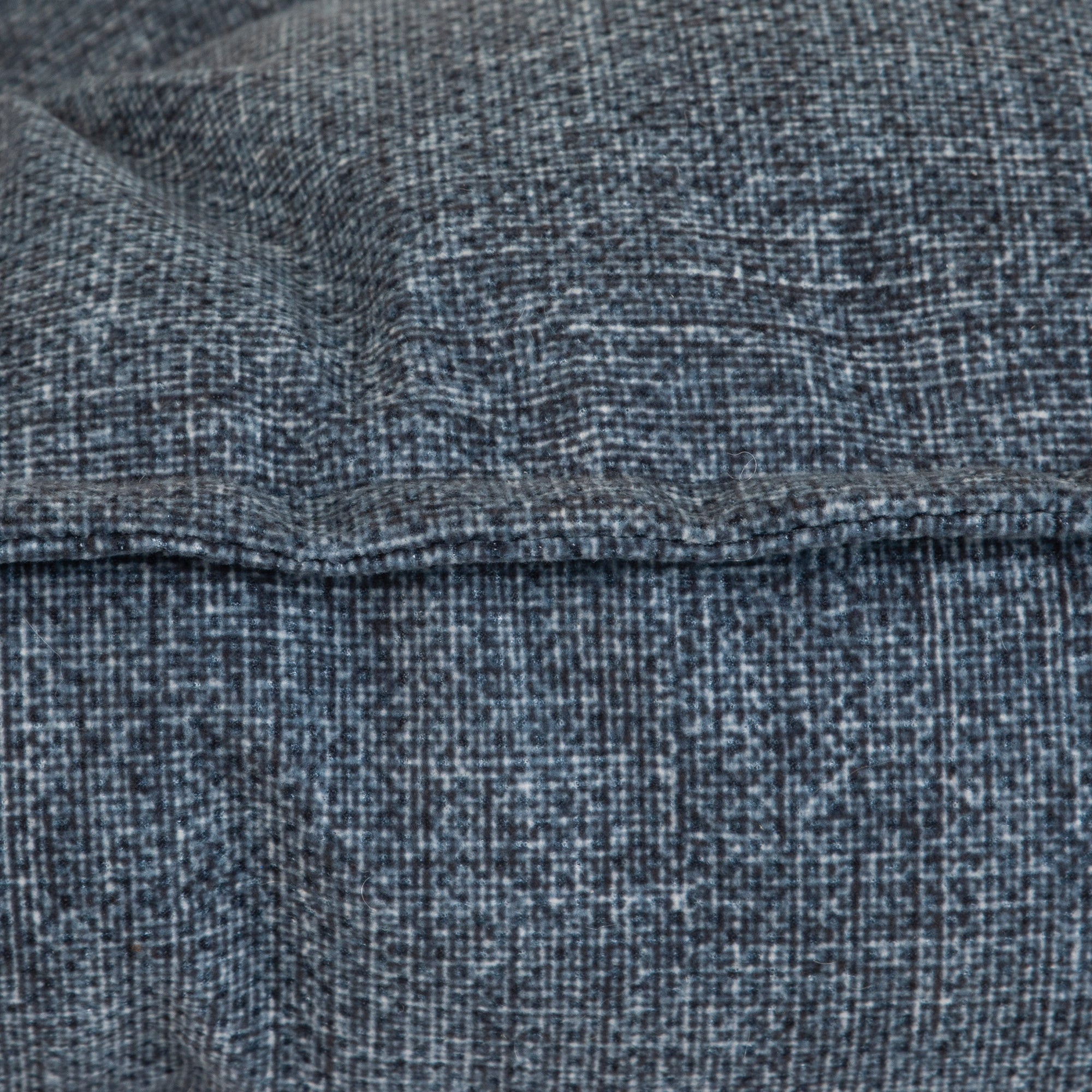 Close-up of a textured blue-gray fabric that resembles a La-Z-Boy Outdoor Millie Mattress Dog Bed, with a visible horizontal seam. The woven pattern features varying shades, creating a subtle checkered effect.