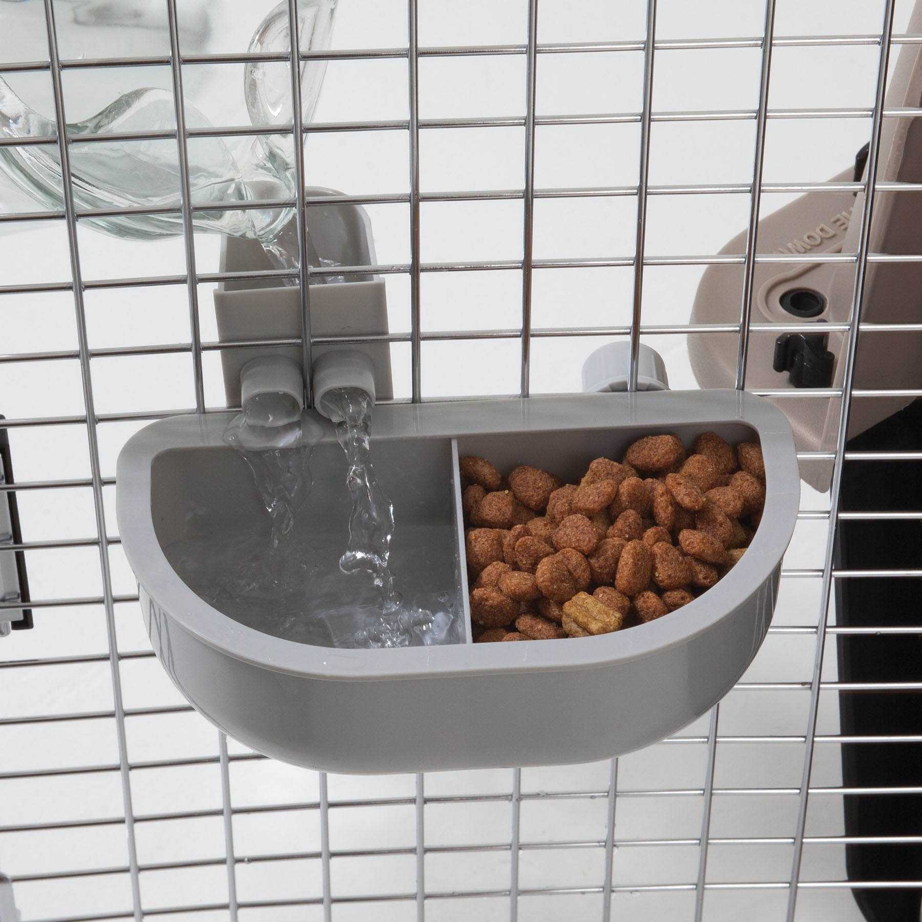 The Pet-mates No Spill Kennel Cup Double Diner by Pet-mates attaches to pet cage bars, featuring a dual feeder with one section for water from a connected bottle and another for kibble. Its BPA and lead-free, ensuring your pets safety.