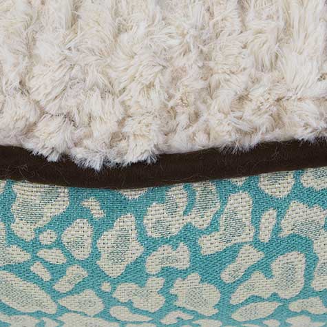 The Pet-mates Two-Sided Fashion Dog Pillow Bed features a close-up fabric detail: white fluffy texture atop a dark brown strip, with turquoise fabric showcasing a light beige leopard print below, all in a cozy, washable design.
